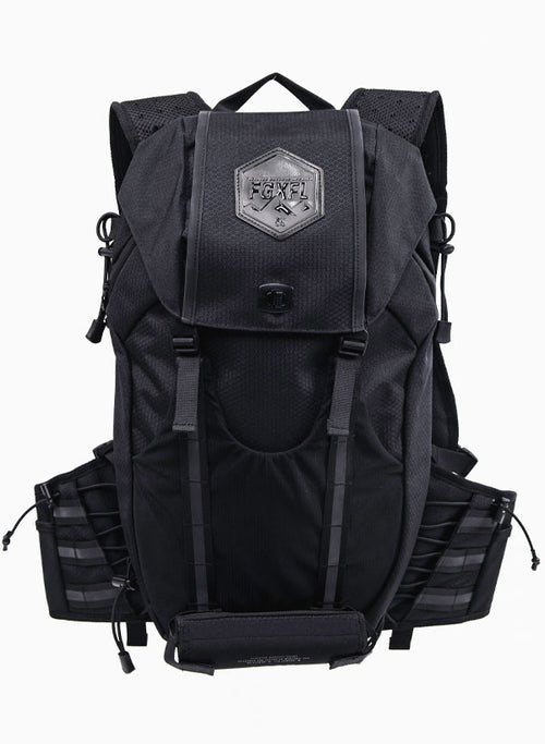 The back of our Apex bag black in color. The top flap of the bag has a  hexagonal patch. The patch reads "ELEVATED OUTDOOR APPAREL" FGXFL above a range of mountains. The top flap has two buckles to buckle to the body of the pack.
