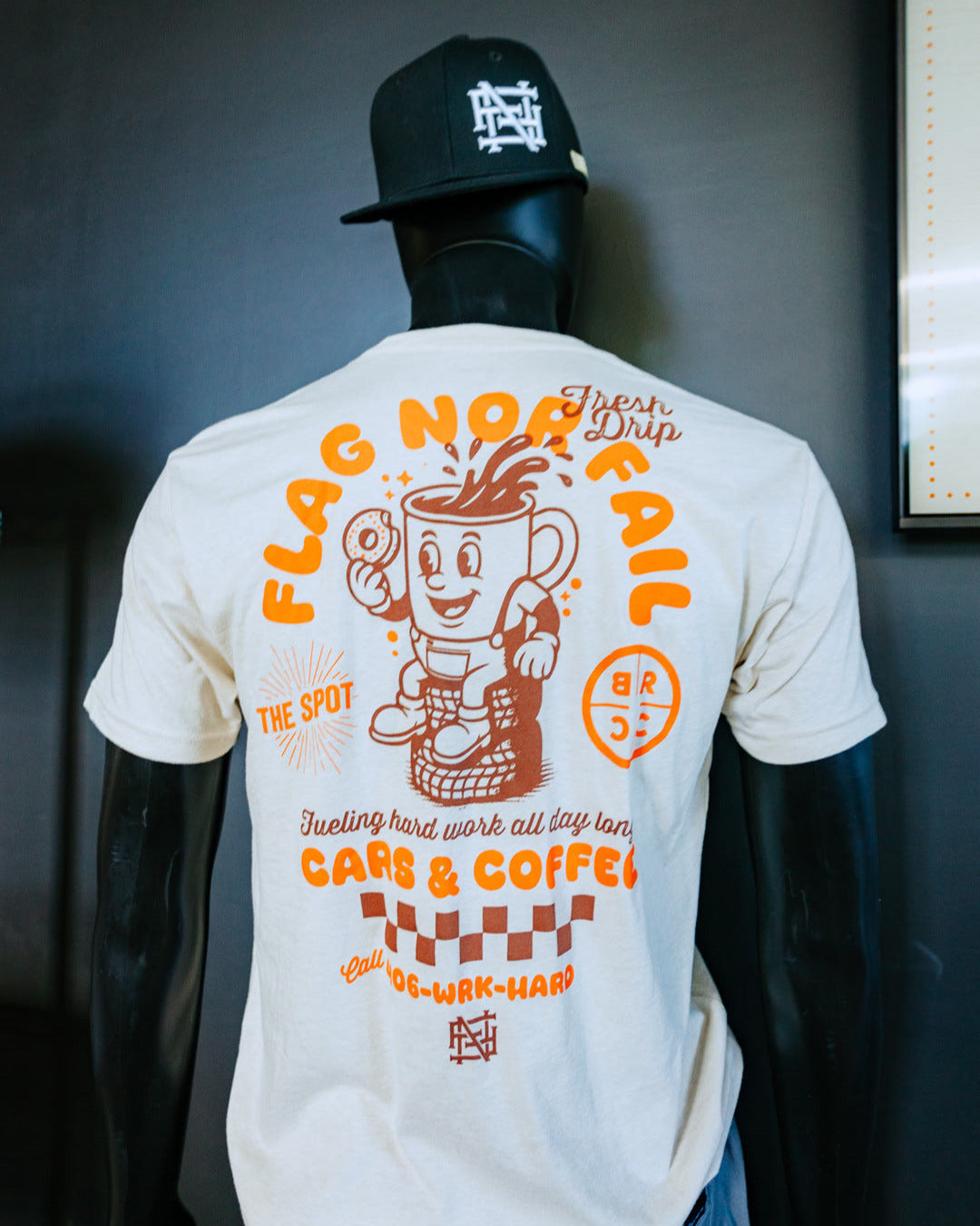 Mannequin wearing a white t-shirt with colorful graphics and text, standing against a dark background.