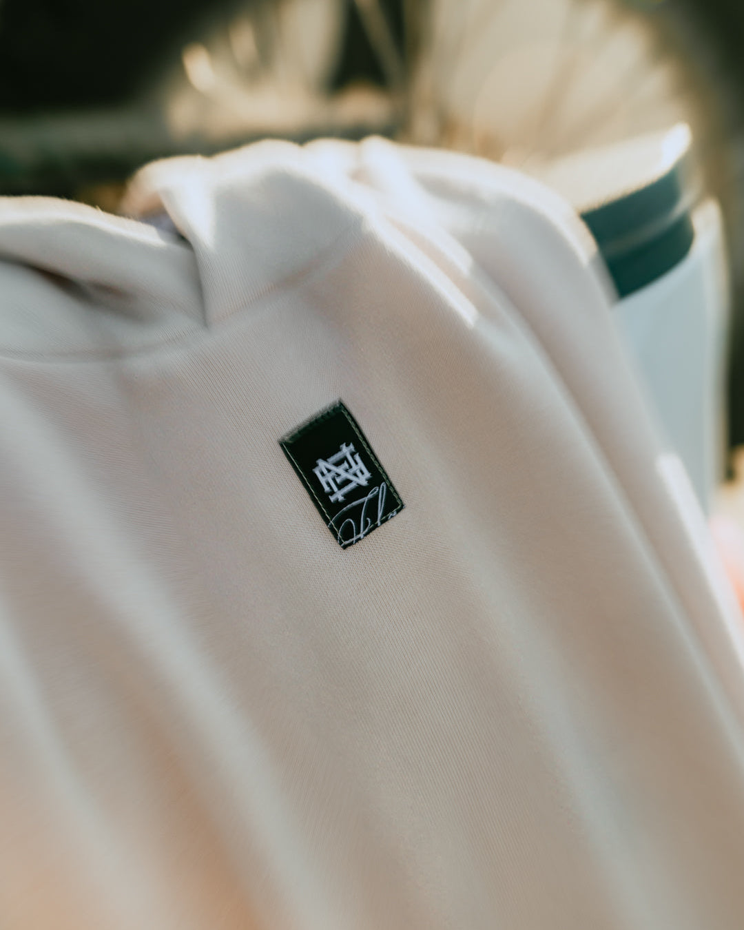 Cream colored hoodie with a black logo on a blurred background